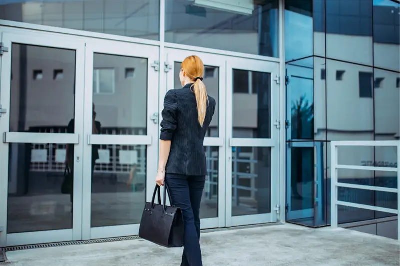 A woman walking towards an office looking like she has lost confidence