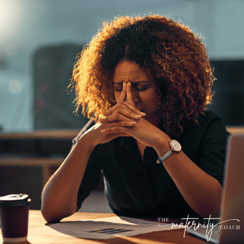 Woman sitting at a desk looking worried with her head resting on her hands